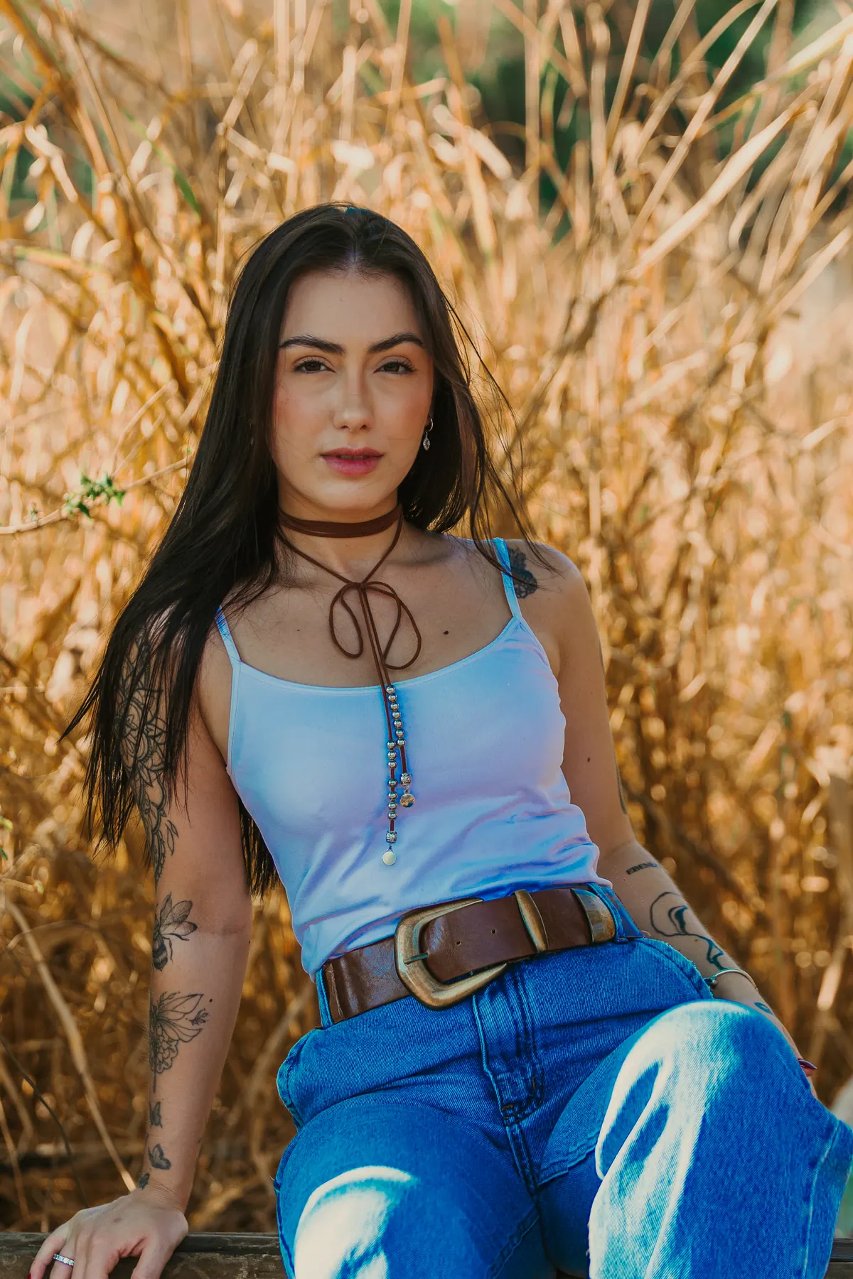 Camila sentada durante um ensaio editorial em ambiente rural